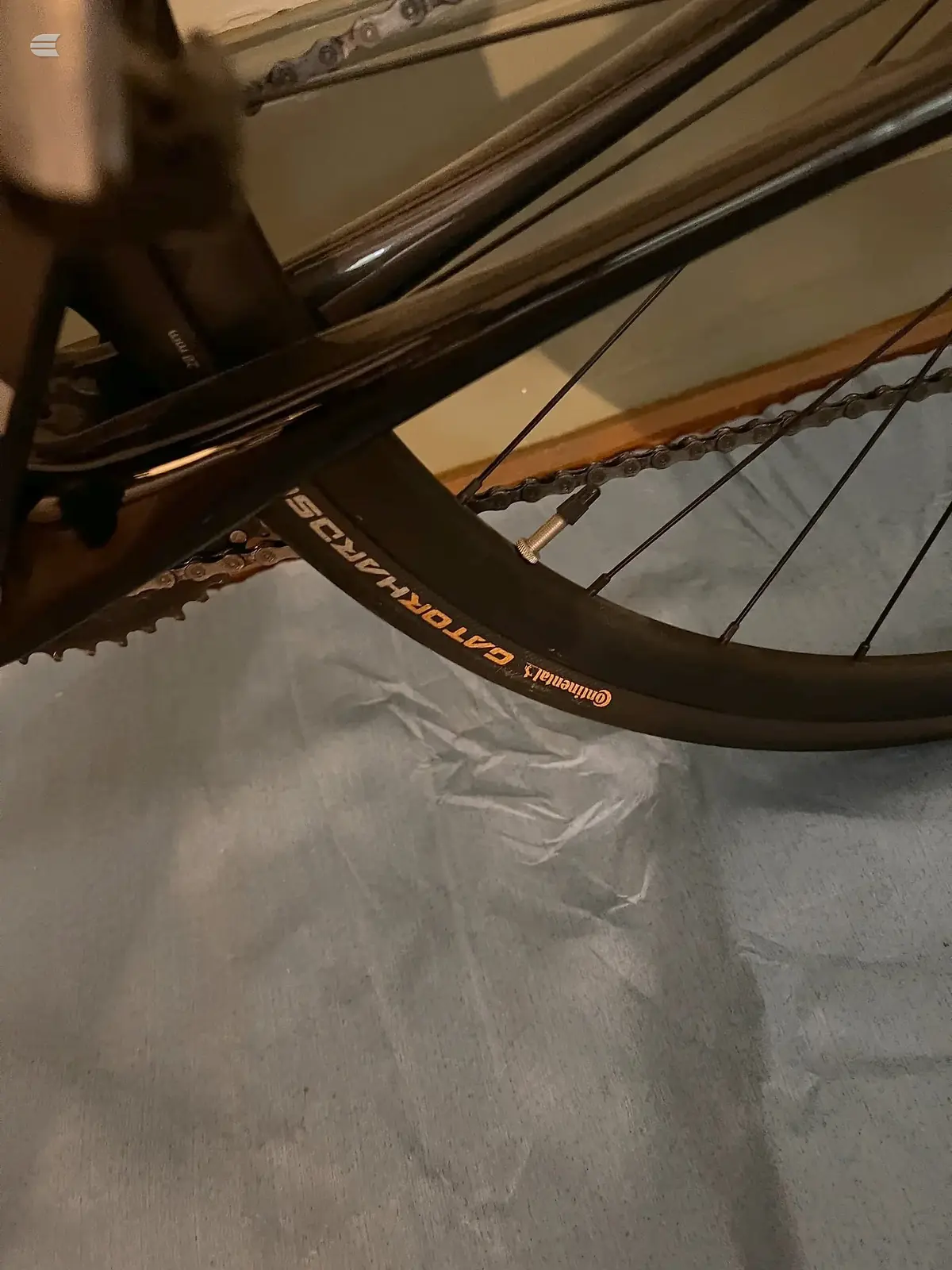 Close-up of Commencal mountain bike drivetrain and chain on grey floor indoors, drive side angle.
