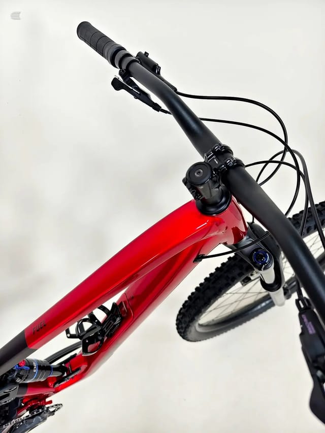 Red and black hardtail mountain bike, non-drive side, angled upward against white sky background.