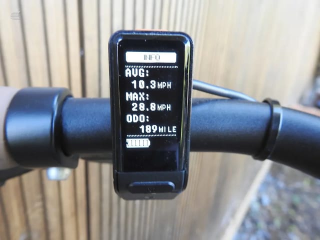 Black bicycle computer mounted on handlebars, displaying average speed 10.9 MPH, maximum speed 28.8 MPH, and odometer reading 189 miles.