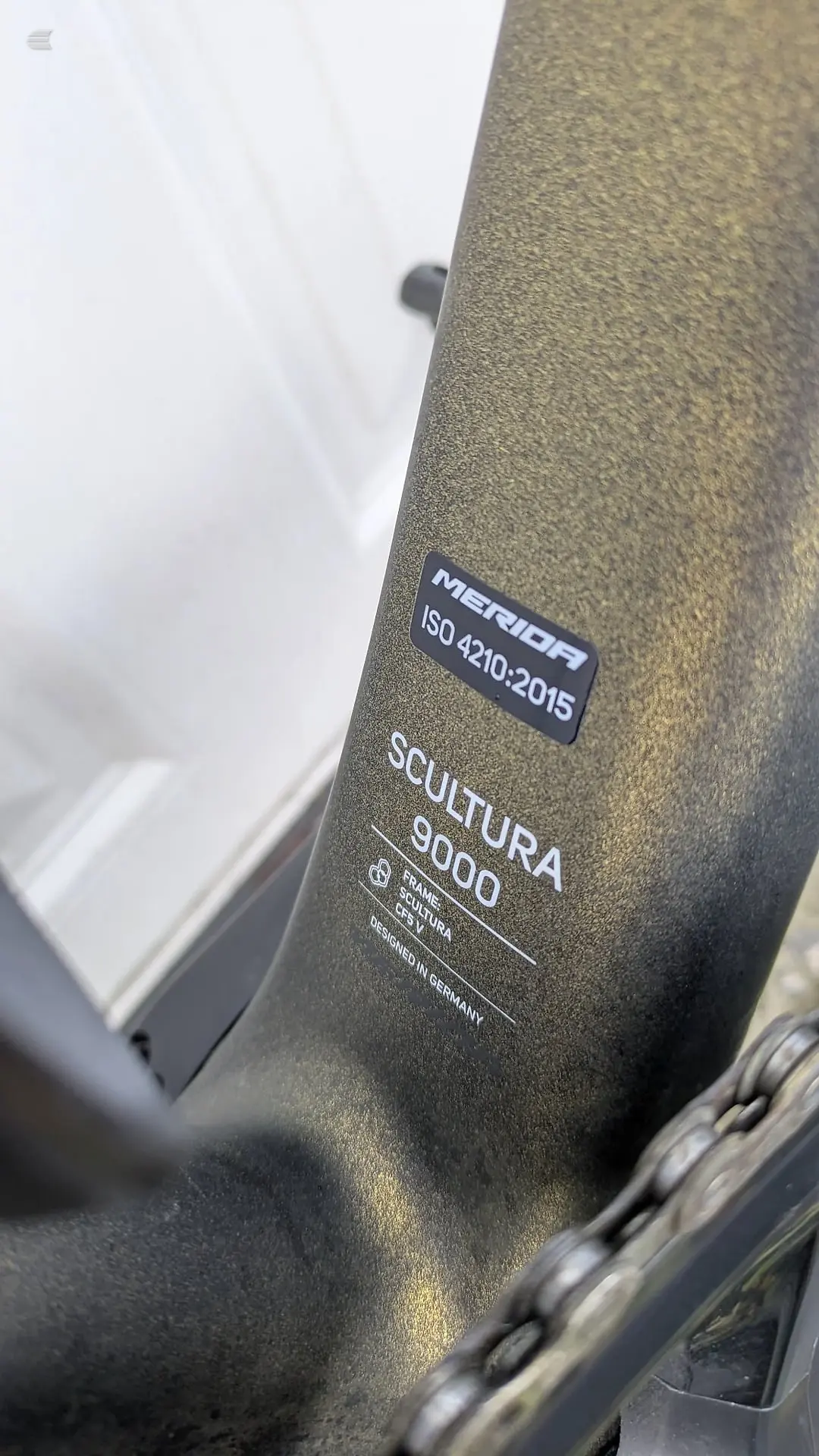 Close-up of Merida Scultura 9000 frame tube showing ISO 4210:2015 certification label and 'Designed in Germany' text, olive-green textured finish.