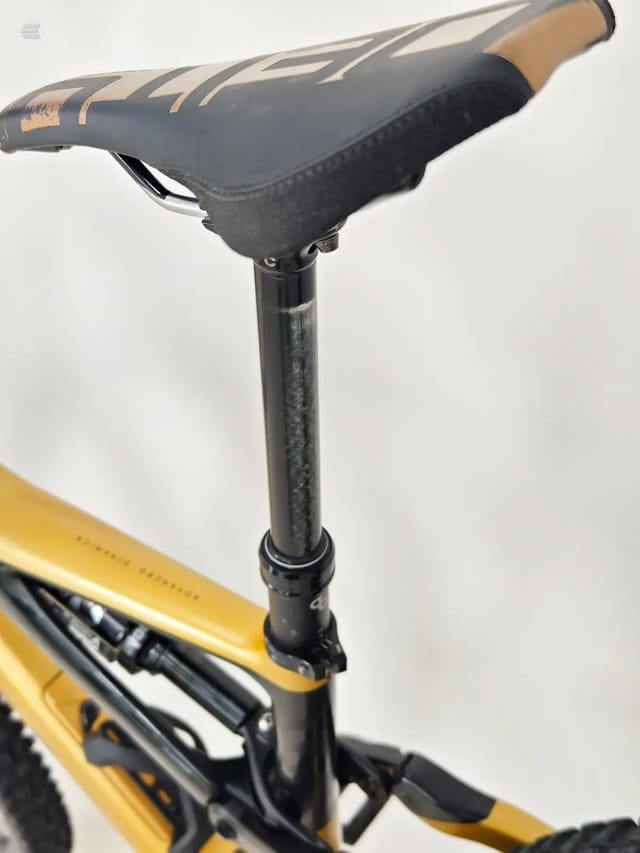 Close-up of a yellow and black bike's seatpost and saddle assembly, non-drive side, against a white background.