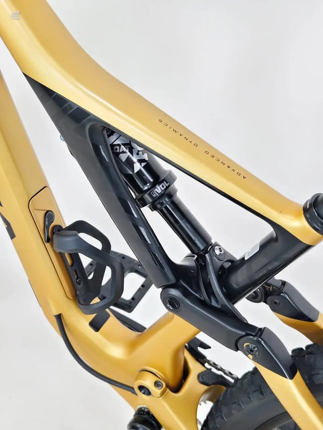 Close-up of yellow full-suspension mountain bike's front shock and headtube area, non-drive side, against white background.