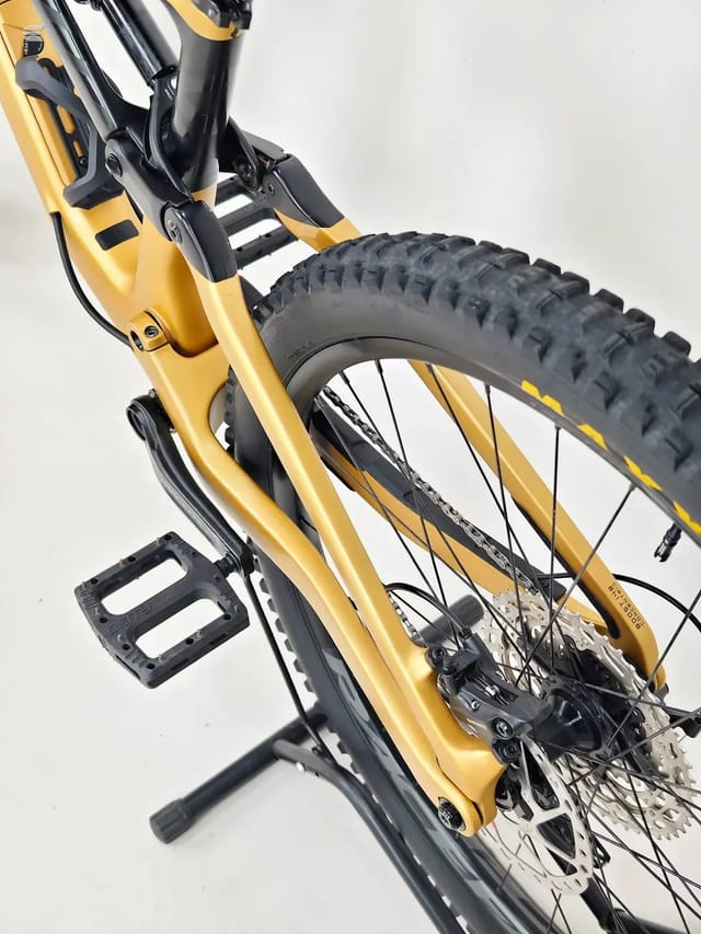 Yellow and black hardtail mountain bike on a stand, drive side, against a white background.