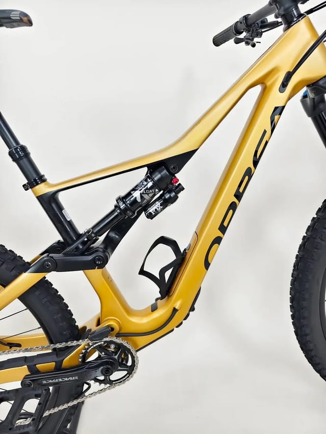 Gold and black full-suspension mountain bike, drive side, angled 3/4 view against white background.