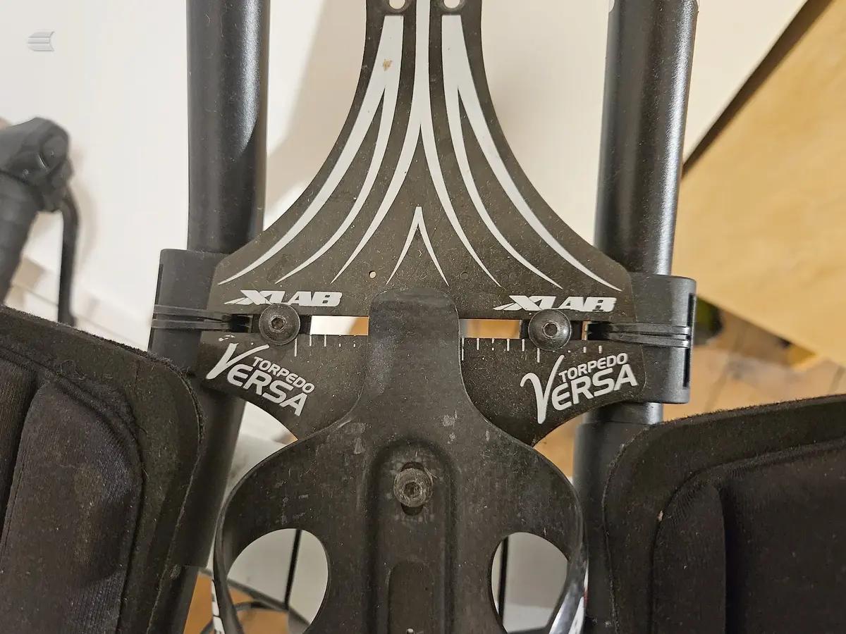 Close-up of black Sram X-Lab Torpedo Versa disc brake calipers on a bicycle, front view against a cream and yellow background.