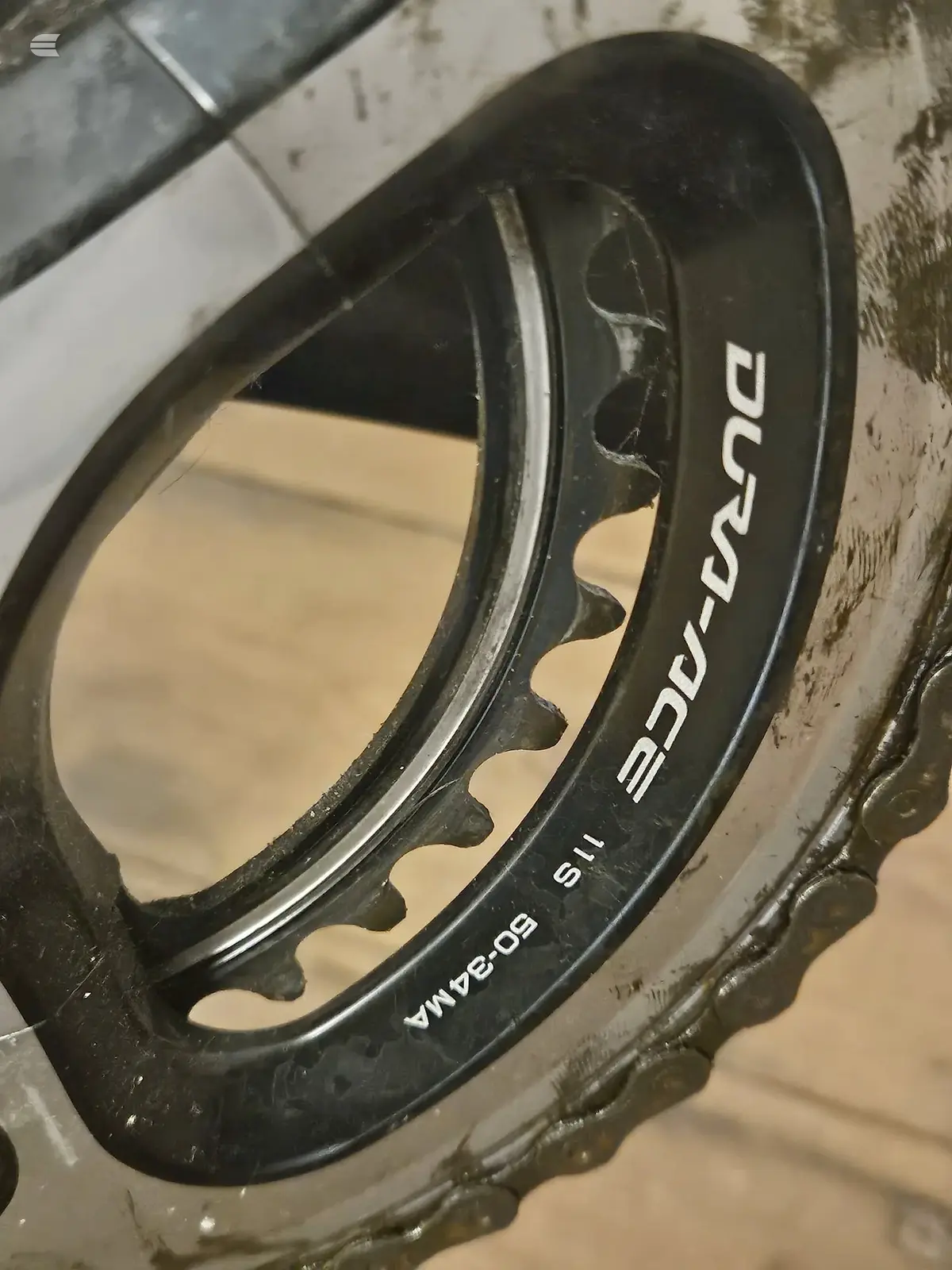 Close-up of black Eddy Merckx bicycle wheel rim with visible spoke detail, angled three-quarter view against beige wall.