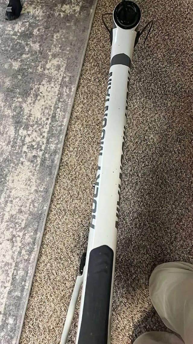 White and black bicycle handlebar and stem assembly on carpet, overhead view. Text reading 'HUUB' visible on white bar tape.