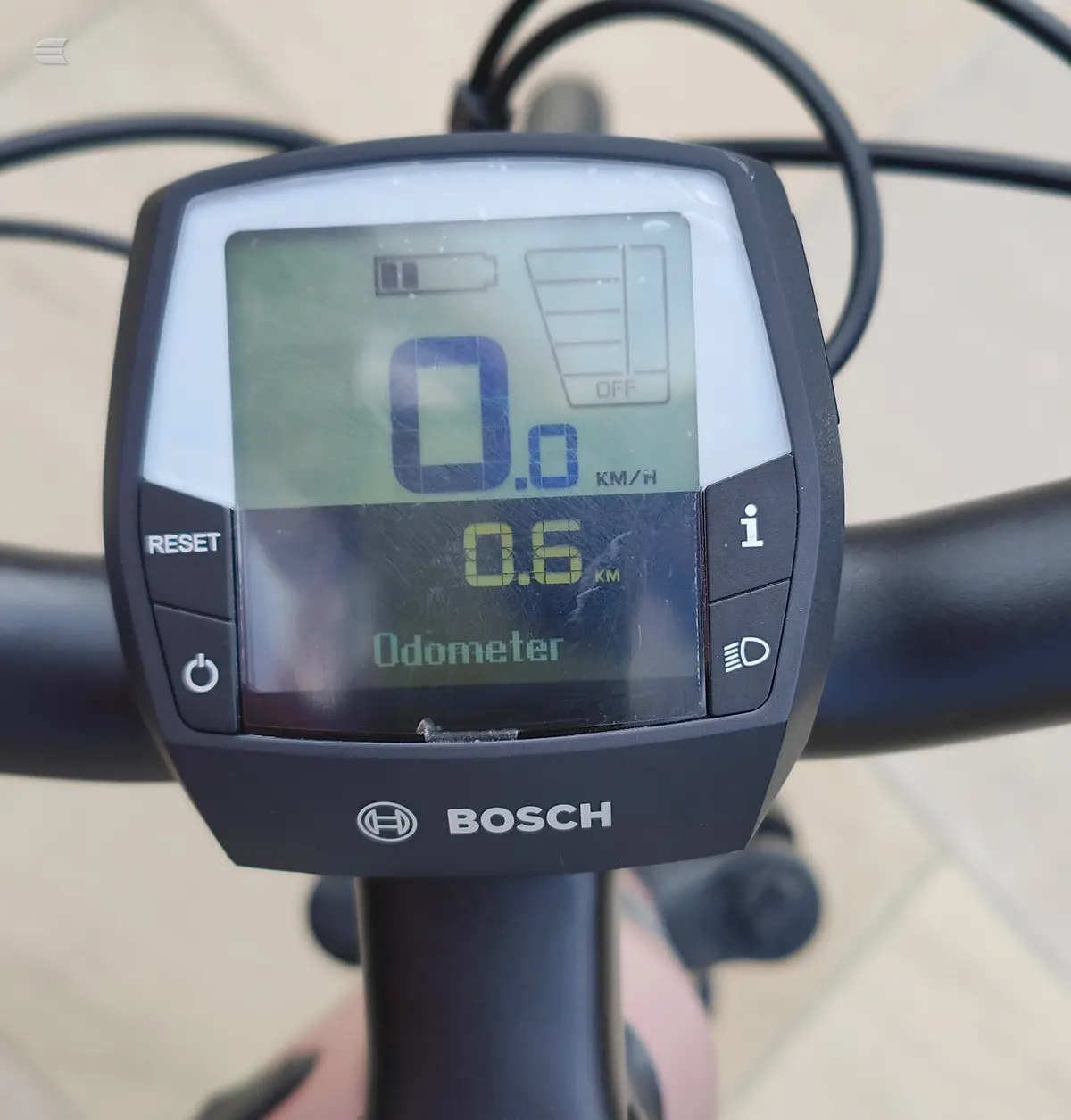 Bosch electric bike display console mounted on handlebars, showing odometer reading 0.6 km and speed 0.0 km/h, against a beige background.