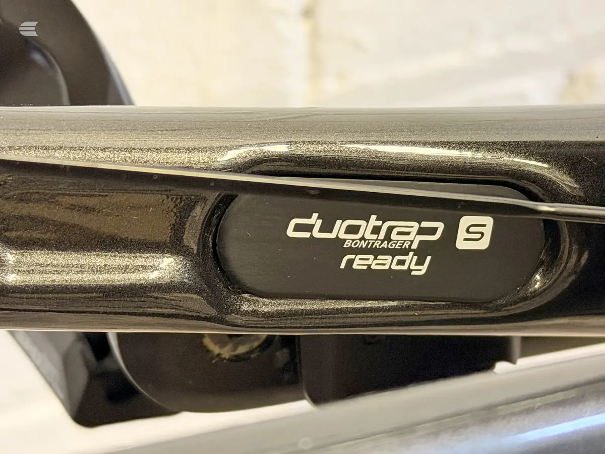 Close-up of Bontrager S Ready crankset and crank arm on black bike frame, drive side, indoors.