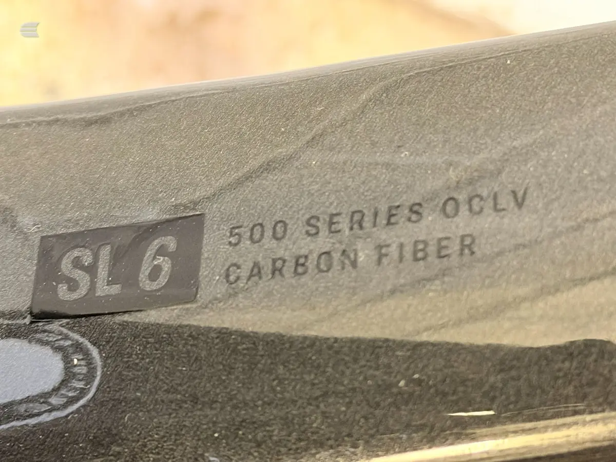 Close-up of carbon fibre frame tube showing 'SL6' and '500 Series OCLV Carbon Fiber' branding, angled view against blurred background.