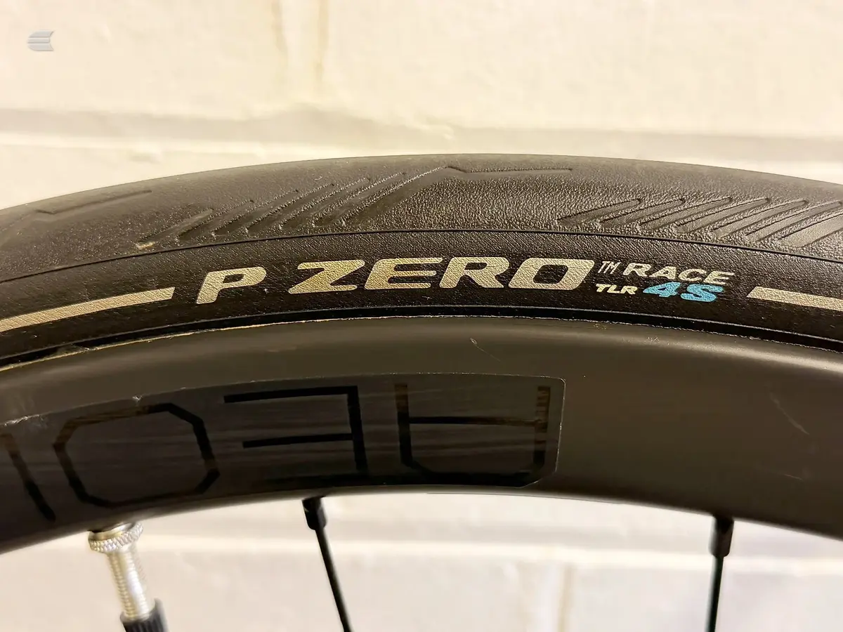 Close-up of Pirelli P Zero Race TLR black road bike tyre on rim, angled view against white background.