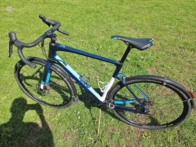 Blue and white Pinnacle road bike on grass, drive side view, handlebars and saddle visible, full frame in shot.