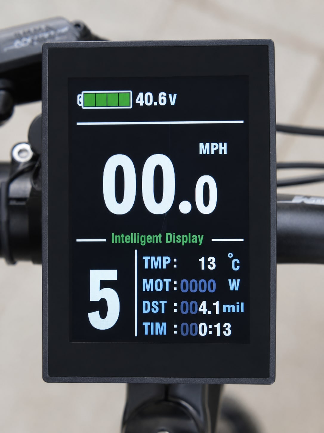 Close-up of an e-bike intelligent display screen mounted on handlebars, showing 40.6V battery level, 00.0 MPH speed, and trip data including temperature, motor