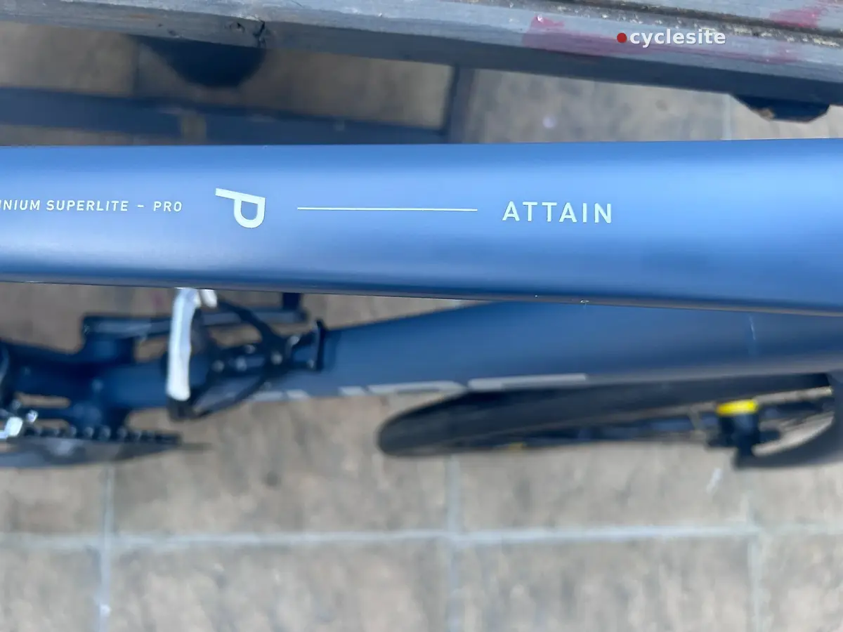 Blue aluminium Superlite Pro bicycle frame tube close-up, showing brand text and model name on the seat tube against a concrete background.