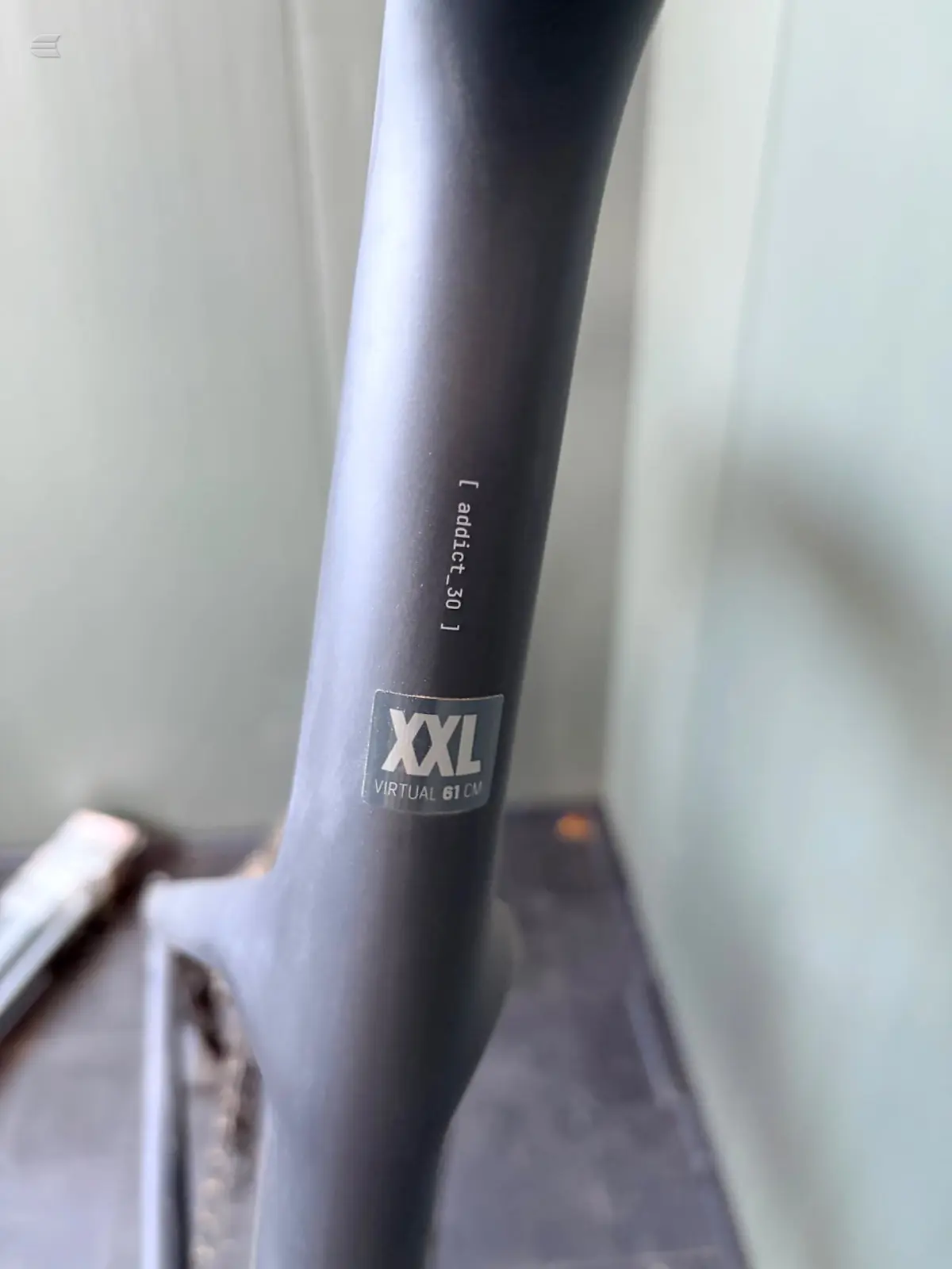 Close-up of black bicycle seatpost showing 'Alutech 30' text and 'XXL VIRTUAL 61 CN' branding label against white background.