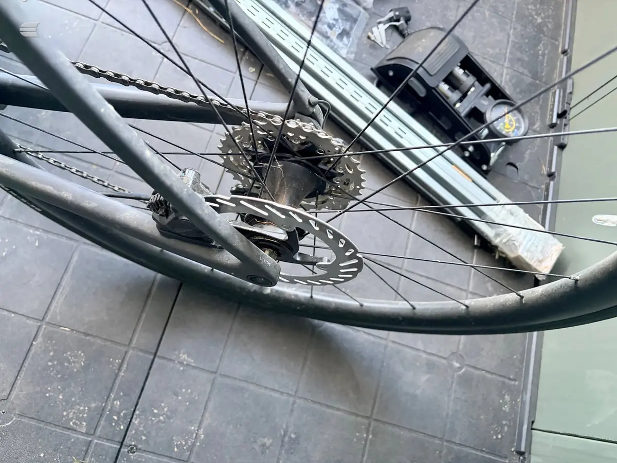 Close-up of rear derailleur and cassette on a mountain bike, drive side, indoors on tiled floor.
