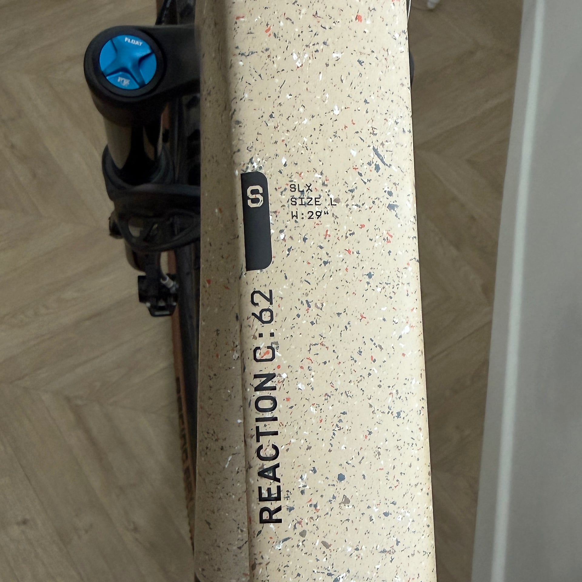 Close-up of cream cork handlebar tape on a Reaction C:62 bicycle frame, showing size L marking and 29-inch width specification, non-drive side angle.