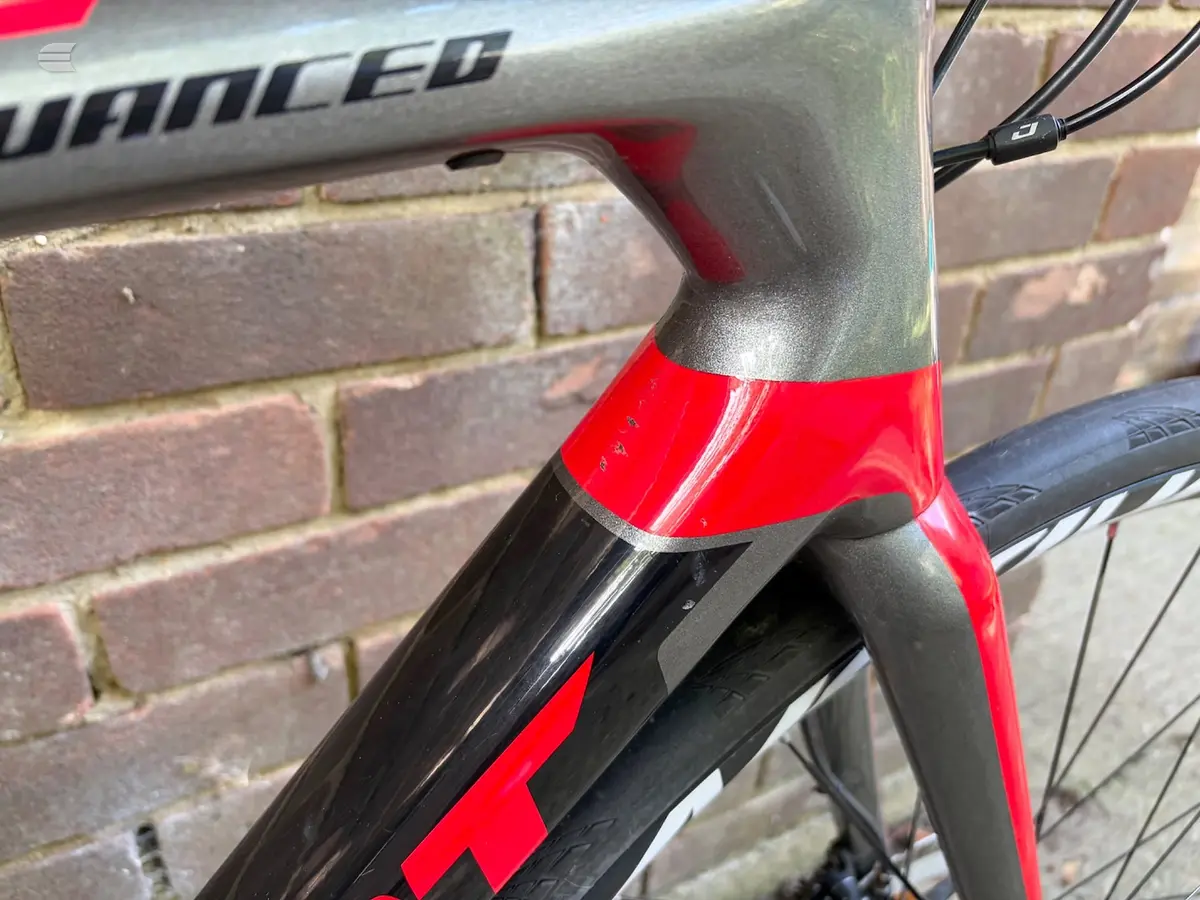 Red and grey United brand road bike frame, non-drive side close-up against a brick wall.