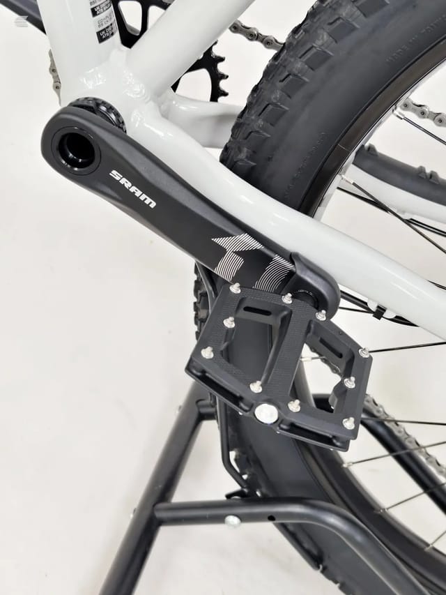 White hardtail mountain bike, close-up of SRAMcrank and pedal area, drive side, against white background.