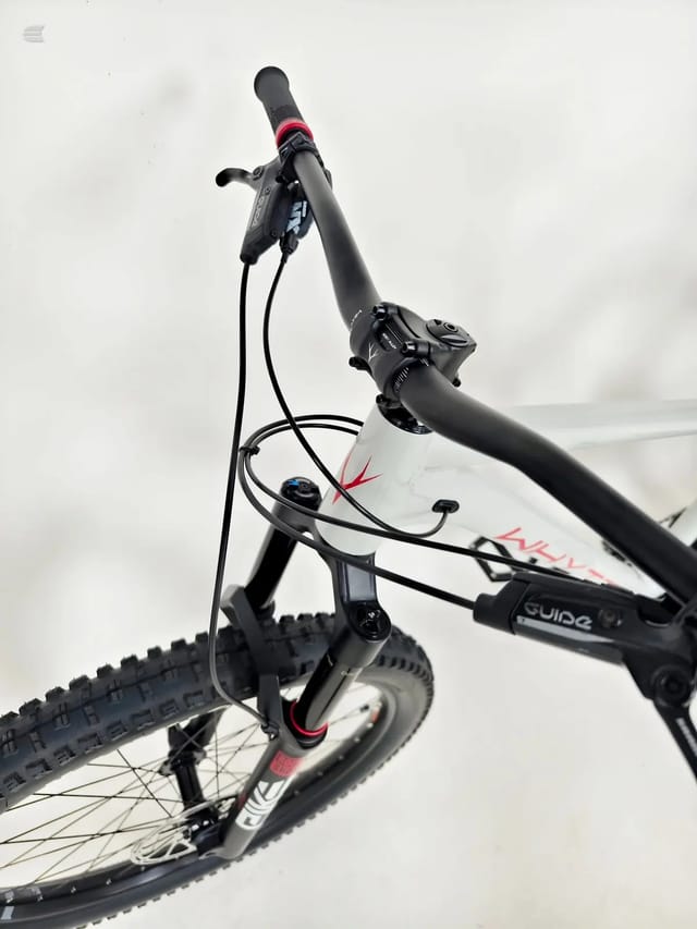 White and black hardtail mountain bike with red accents, angled upward against white background, non-drive side view.