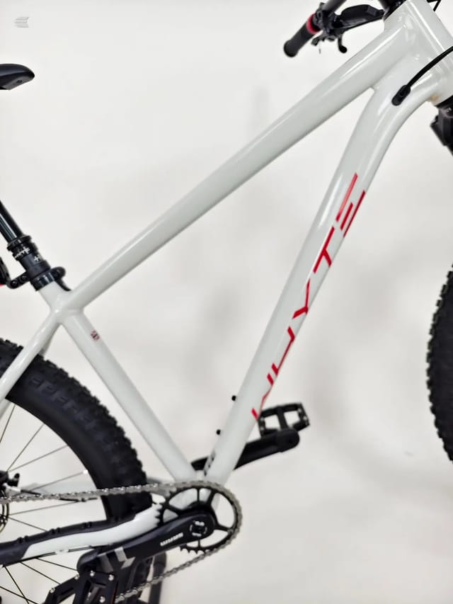 White and red hardtail mountain bike with black components, three-quarter view from drive side, against white background.