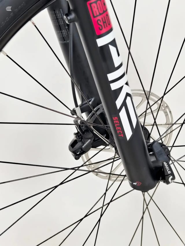 Close-up of black and white mountain bike front wheel with disc brake, spokes and hub visible, non-drive side angle against white background.