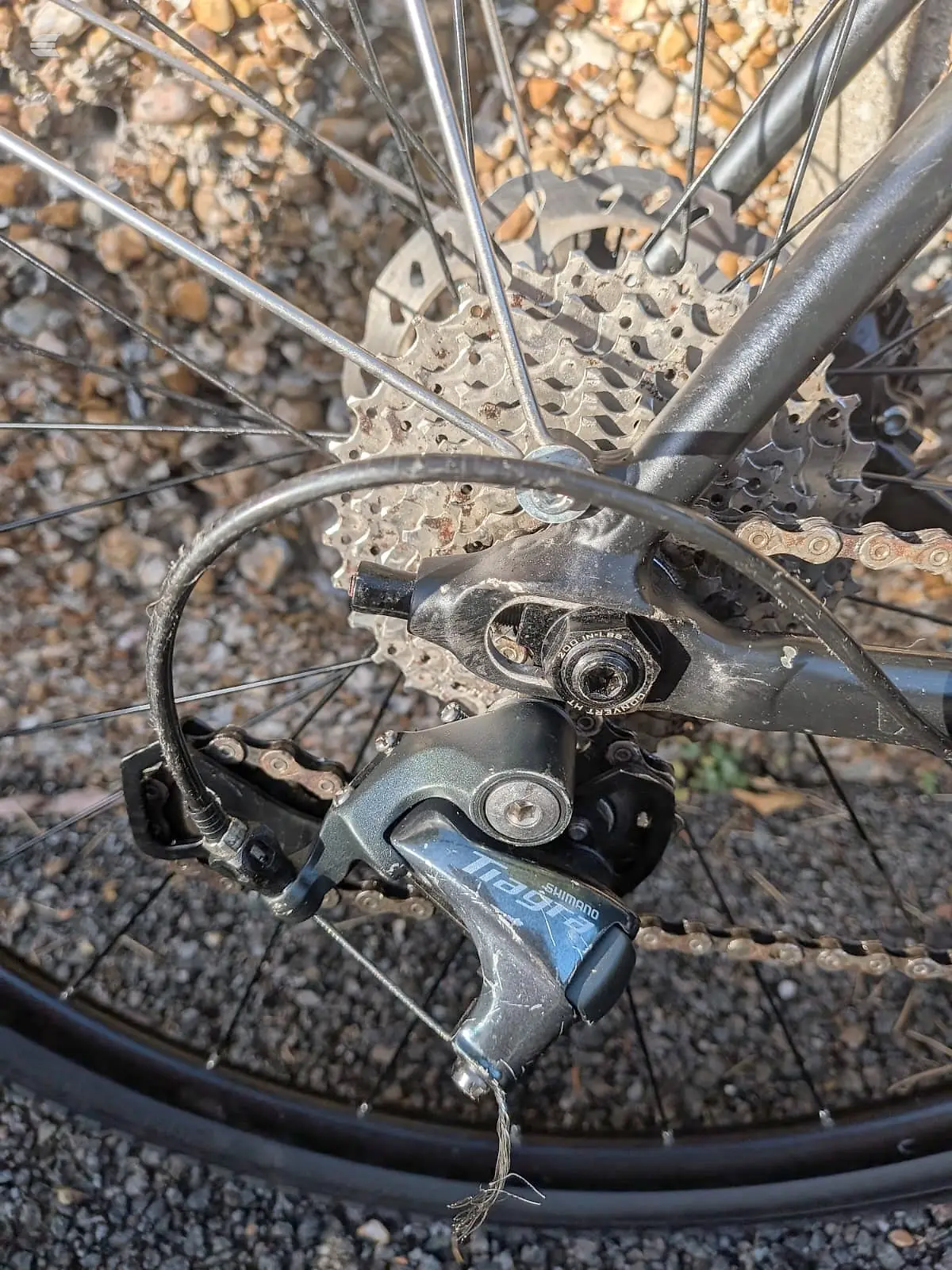 Shimano hydraulic disc brake and cassette on mountain bike rear wheel, drive side, on gravel ground.